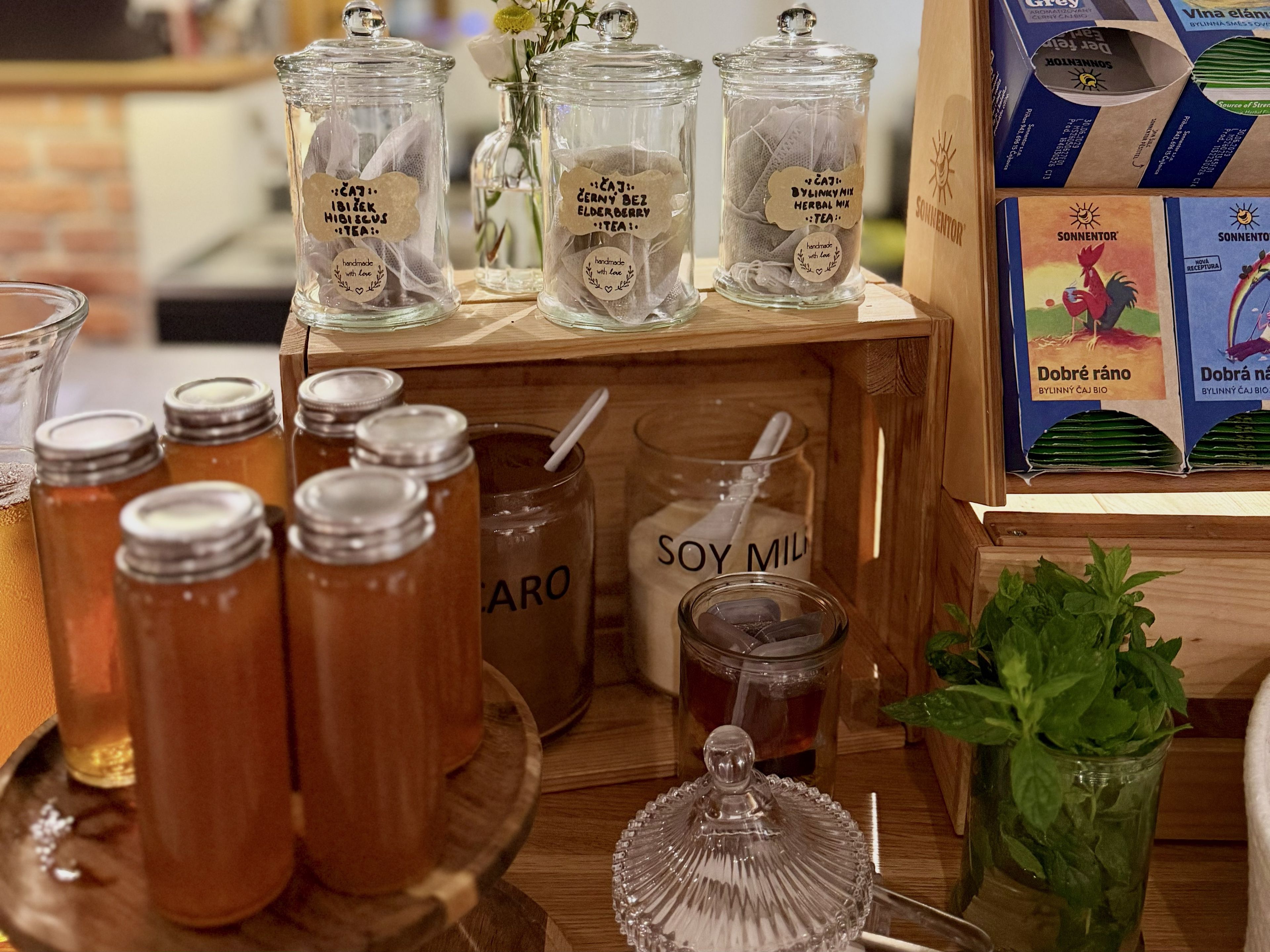 A variety of glass containers with labels, a wooden crate with books, and a glass jar labeled 'SOY MILK'.