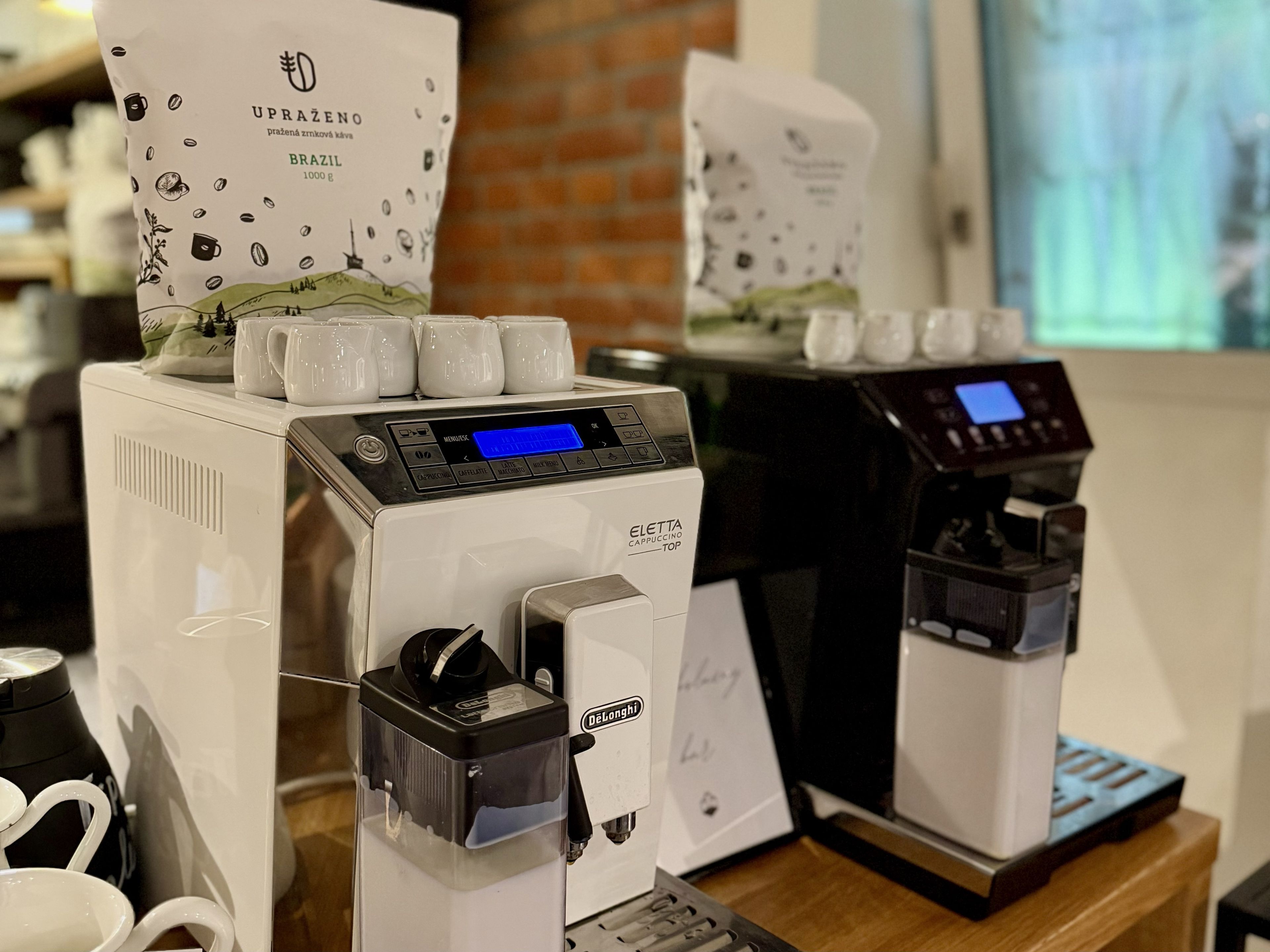 Una cafetera con pantalla digital y una bolsa de café con la etiqueta 'UPRAZENO BRAZIL 1000 g'.