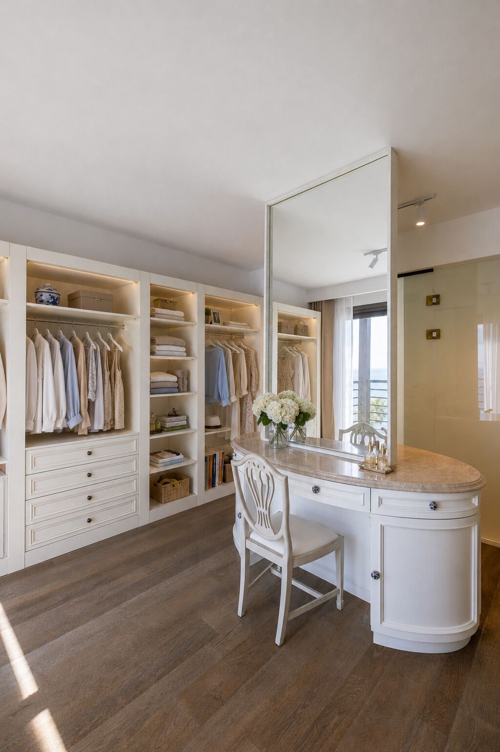 A walk-in closet with multiple shelves and drawers, a vanity with a mirror, and a wooden floor.