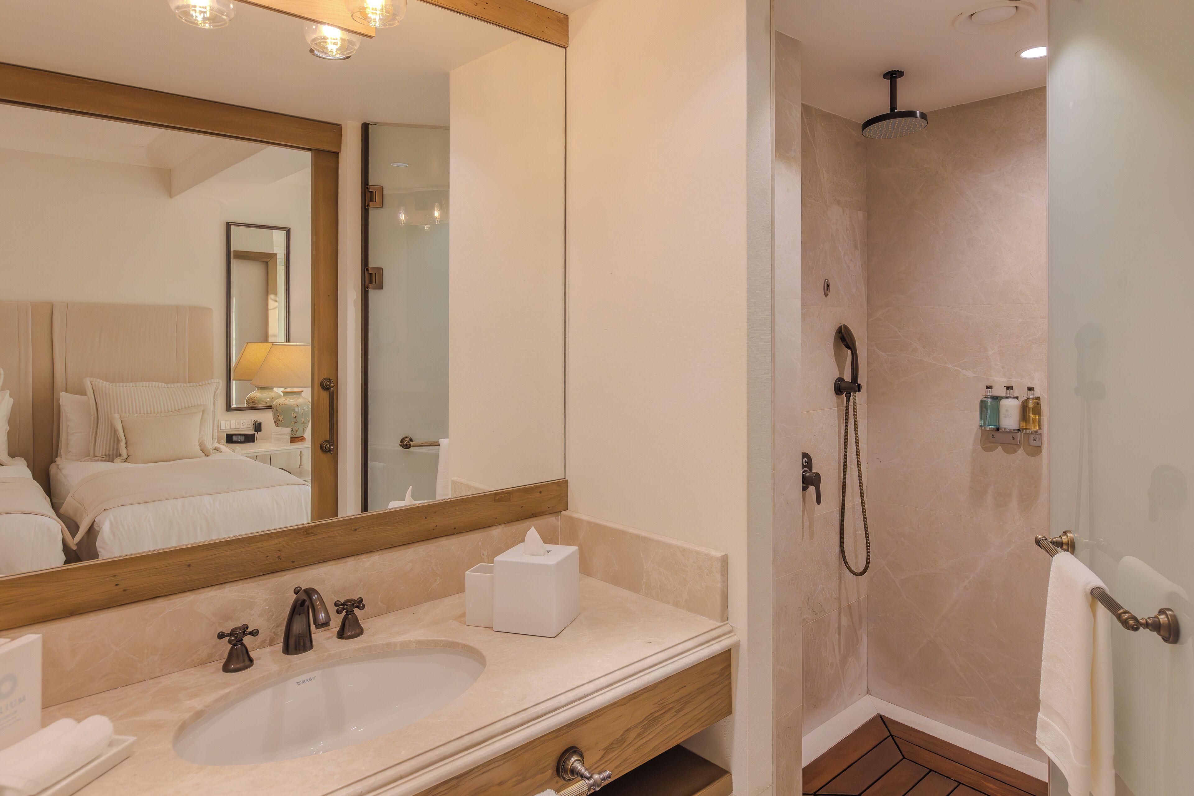 Un baño moderno con un espejo grande, lavamanos dobles, ducha y tocador de madera.