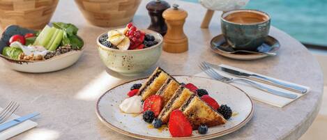 Ein Frühstücksbuffet mit Kuchen, Erdbeeren, Blaubeeren und einer Schale Obstsalat.