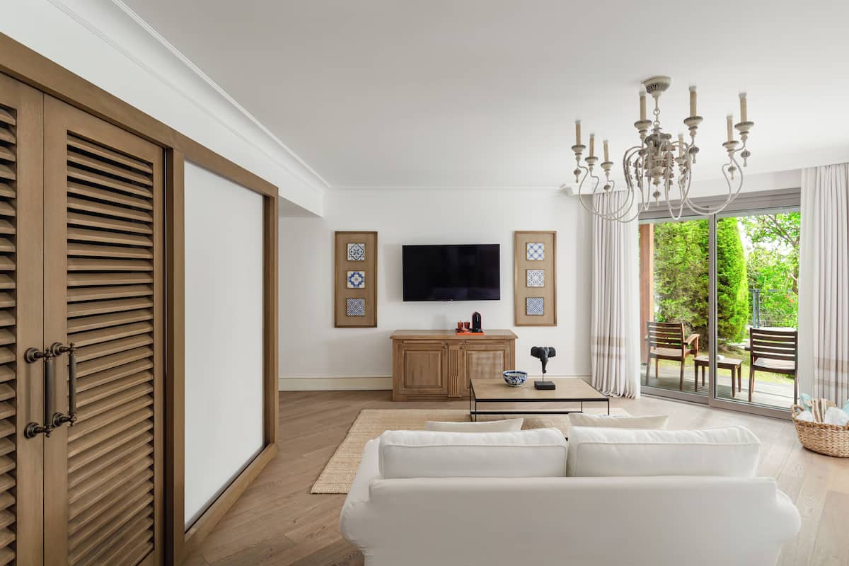 A modern living room with a sofa, a television, wooden cabinets, and a chandelier.