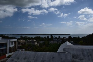 A coastal residential area with houses, a body of water, and a distant island. - Mountain View Apartment (La Gaulette)