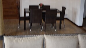 Un coin repas avec une table et des chaises, un vase rempli de fleurs et un plancher en bois.
