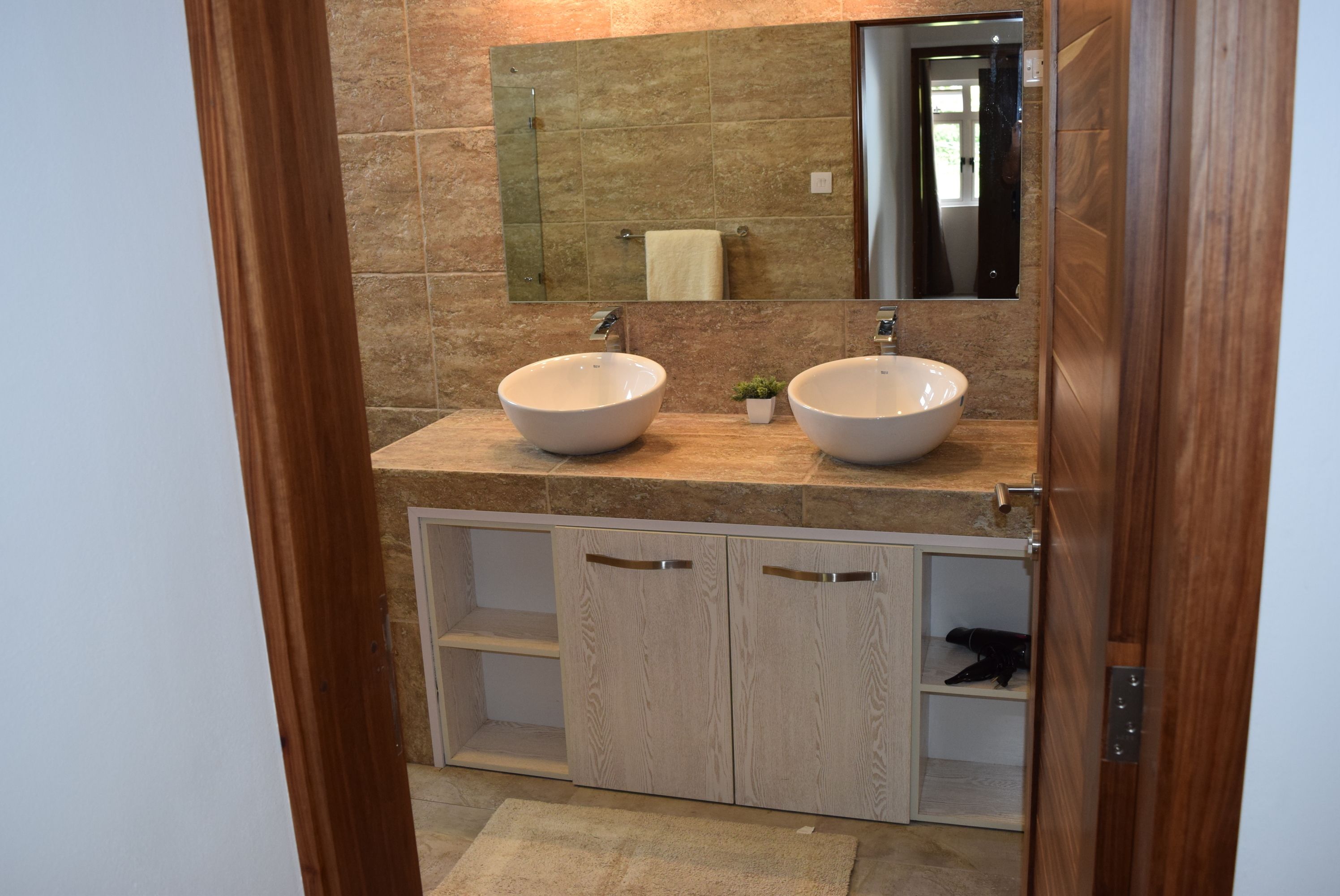 A bathroom with two sinks, a mirror, and wooden cabinets.