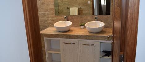 A bathroom with two sinks, a mirror, and wooden cabinets.