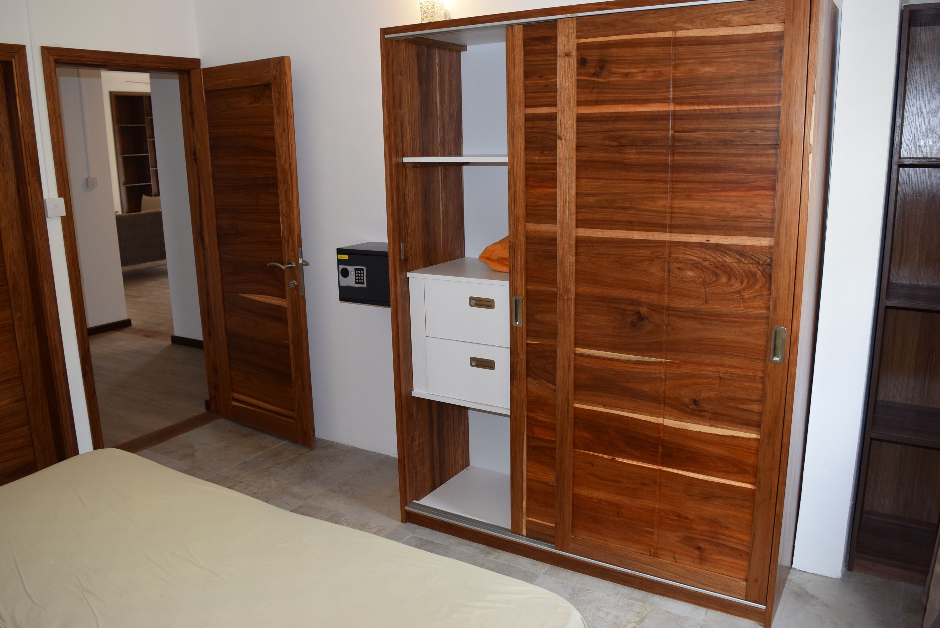 Une chambre à coucher comprenant un lit, une armoire en bois avec plusieurs compartiments et un petit meuble blanc.