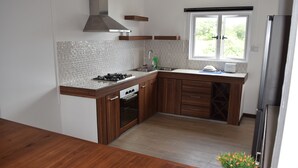Une cuisine moderne avec des meubles en bois, un évier en acier inoxydable et une fenêtre donnant sur un paysage verdoyant.