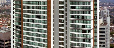 Un edificio de gran altura con el nombre "SOMERSET" en la parte superior. Presenta varios pisos con un diseño arquitectónico moderno, amplias ventanas y una zona de piscina en la azotea.