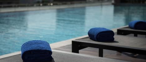 Zona junto a la piscina con sillones de descanso y toallas.
