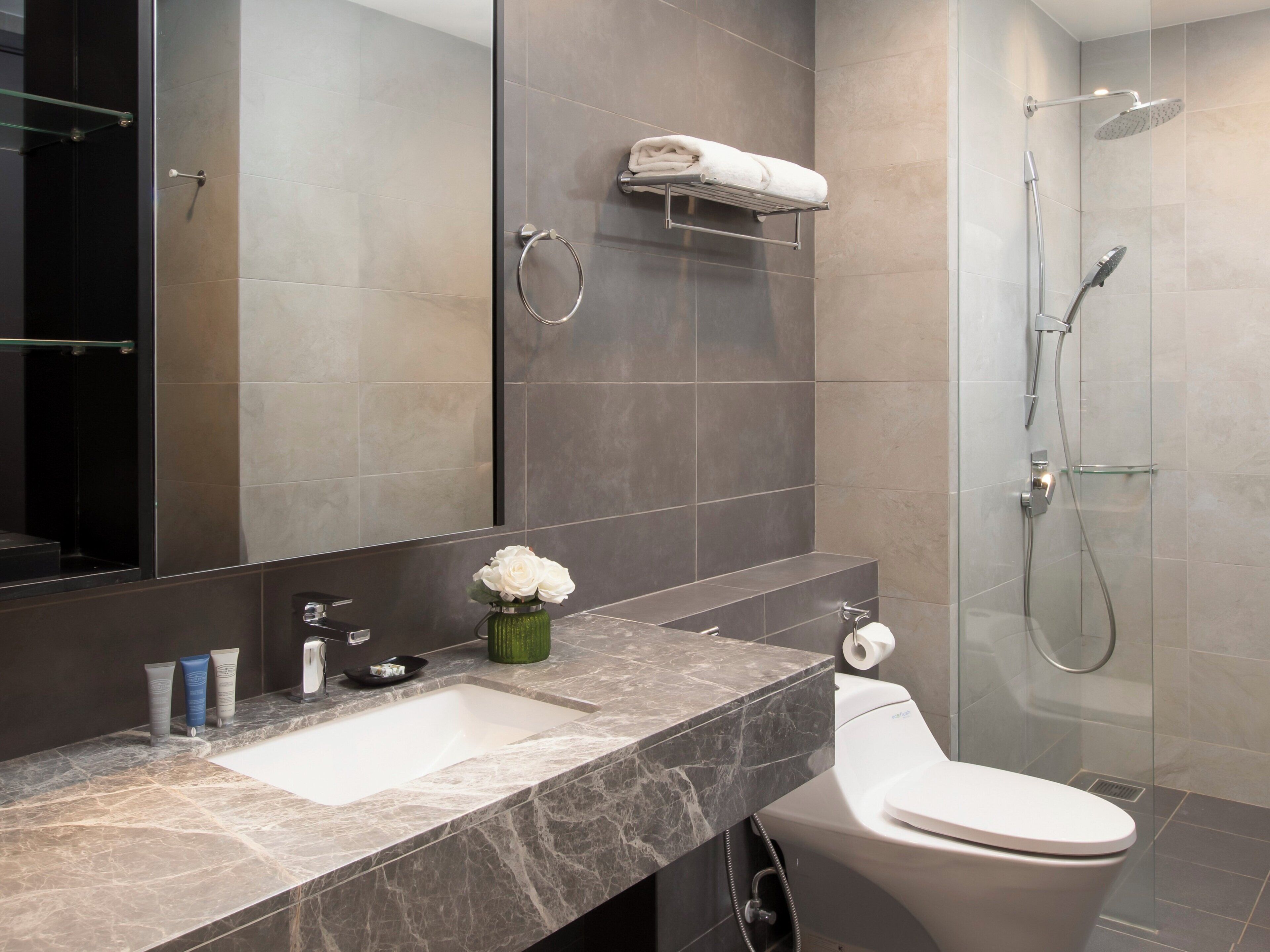 Une salle de bain moderne avec un lavabo en marbre, des toilettes, une douche en verre et un grand miroir.