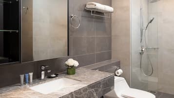 Une salle de bain moderne avec un lavabo en marbre, des toilettes, une douche en verre et un grand miroir.