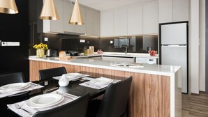 A modern kitchen with a central island, black chairs, and a dining table set for four. - Somerset Damansara Utama Petaling Jaya (Petaling Jaya)