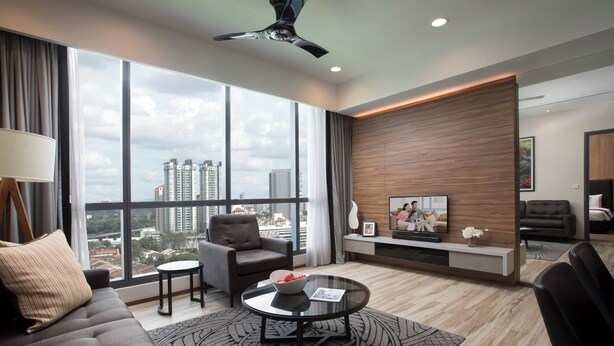 A modern living room with a sofa, armchair, coffee table, and a TV on a wooden accent wall. - Somerset Damansara Utama Petaling Jaya (Petaling Jaya)