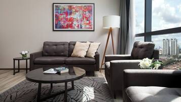 A modern living room with a grey sofa, a round coffee table, and a floor lamp. A colorful abstract painting is on the wall, and a cityscape is visible through the window.