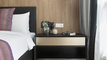 A modern bedroom with a wooden wall, a bed with white bedding, a bedside table with a vase of flowers, and a hanging pendant light.