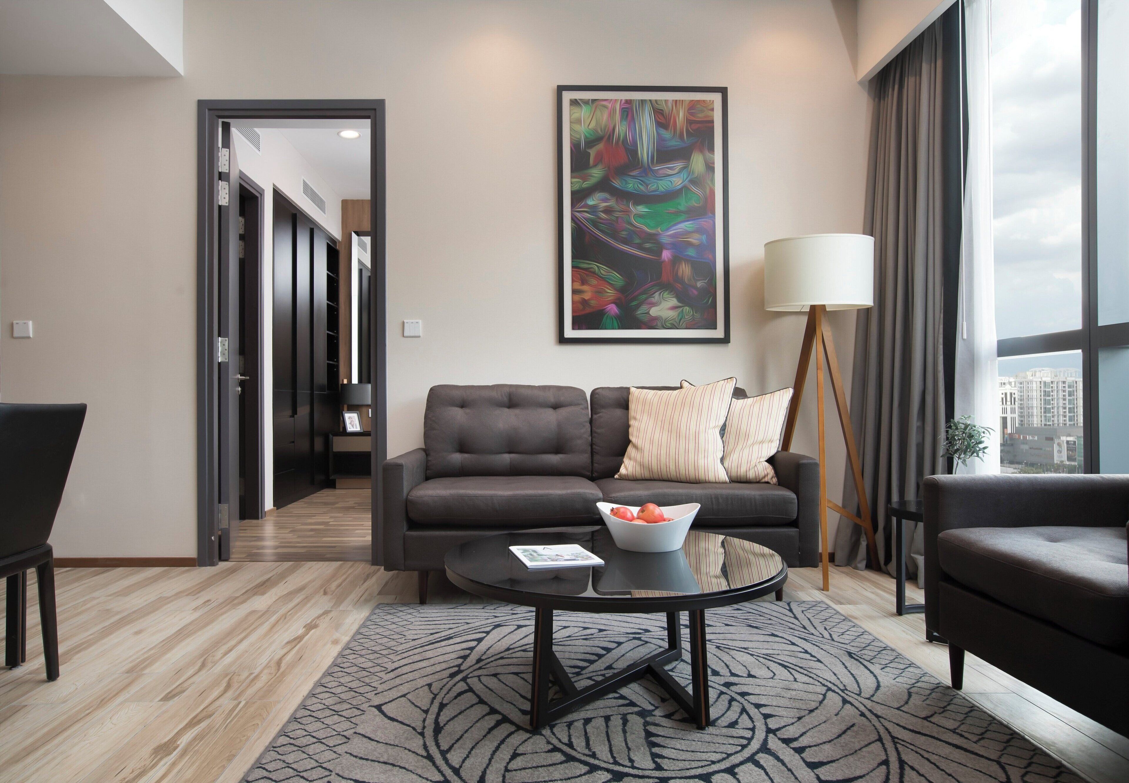 A modern living room with a sofa, coffee table, and a large abstract painting.