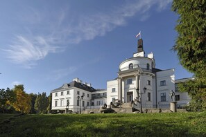 Een groot, wit gebouw in klassieke stijl, met een centrale koepel en een vlag erop.