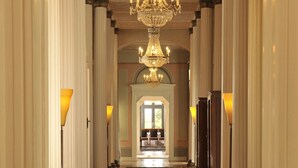Un vaste hall d’entrée agrémenté d’un lustre, de colonnes et de lampes.