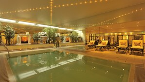Un espace piscine agrémenté de chaises longues et de plantes en pot.