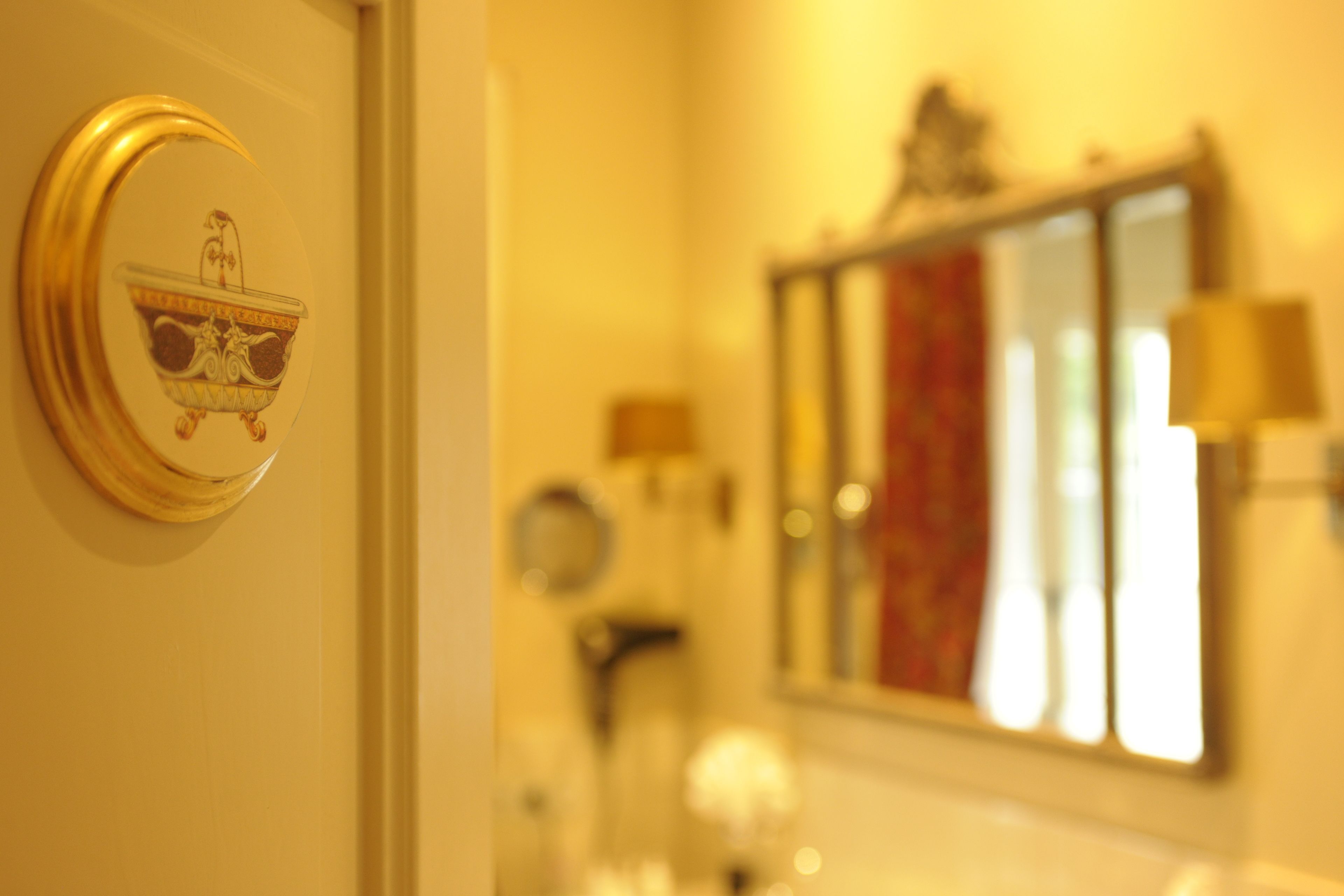 A bathroom with a bathtub, a mirror, and a wall-mounted light fixture.