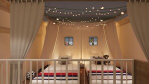 A cozy bedroom with two beds, a nightstand, a teddy bear, and a window with a cartoon character. - Iway International Holiday Apartment (Guangzhou)