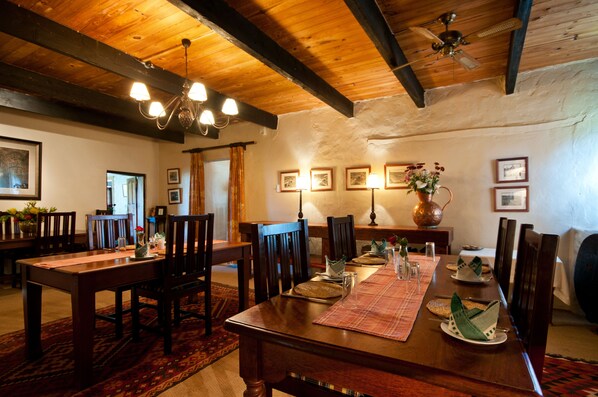 A dining area with wooden tables and chairs, a chandelier, and framed pictures on the walls.