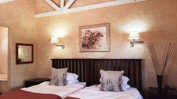 A hotel room with two beds, a wooden headboard, a framed zebra painting, wall-mounted lamps, and a mirror.