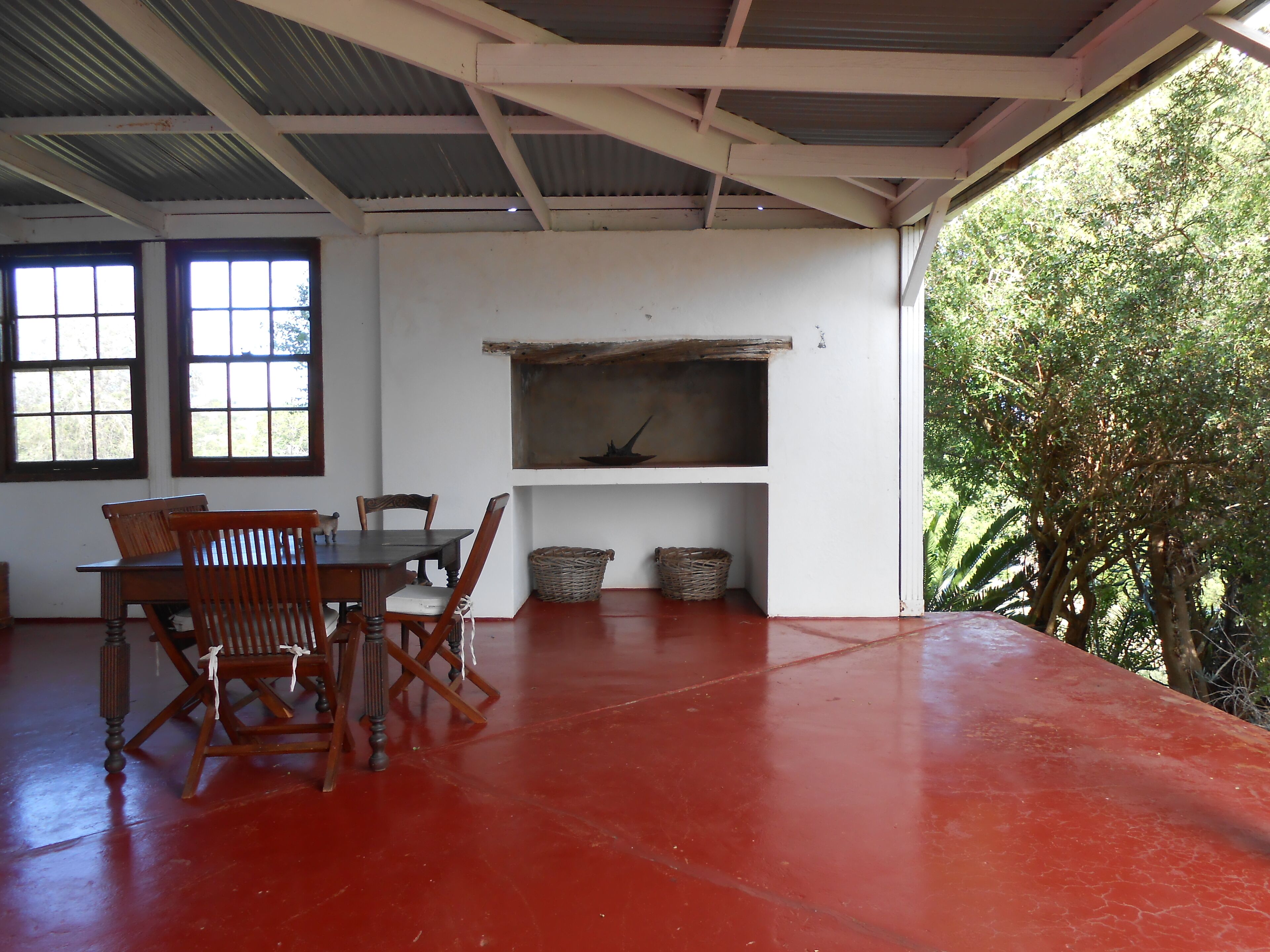A room with a red floor, wooden furniture, a white wall, and a metal roof.