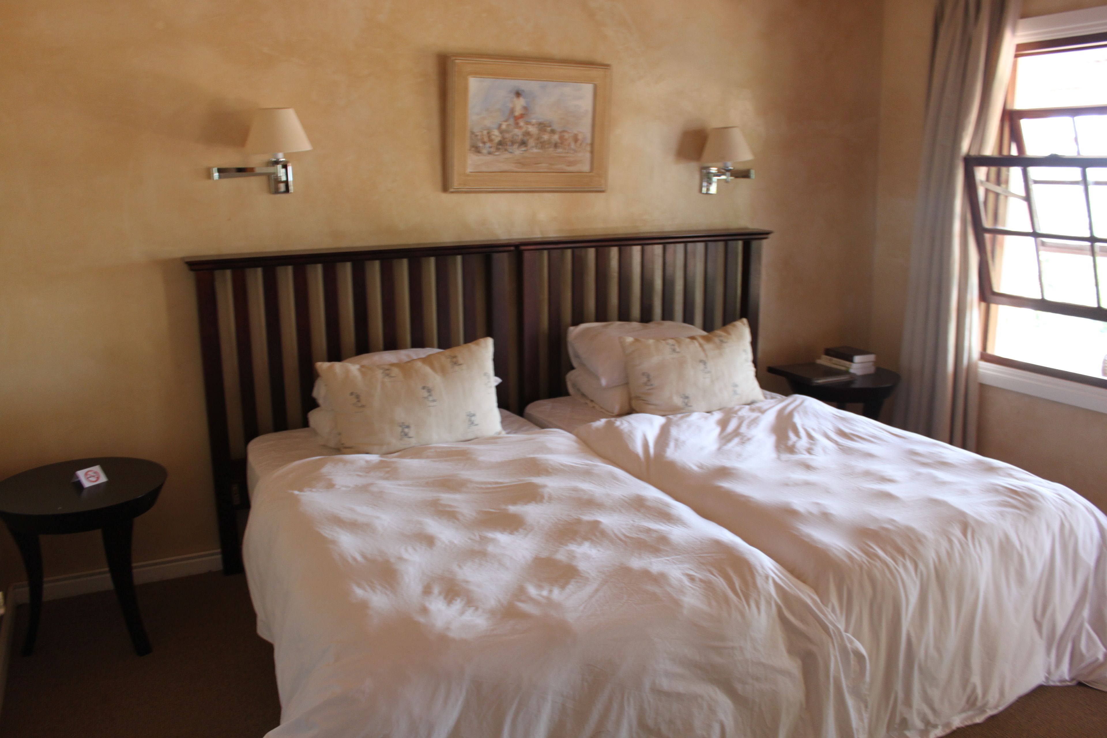 A hotel room with a large bed, two bedside tables, and a painting on the wall.