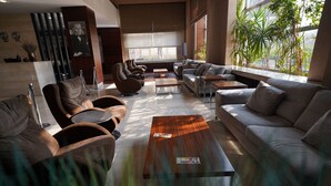 Un área de estar moderna con sofás de cuero, una mesa de centro de madera y ventanas amplias que dejan entrar luz natural.