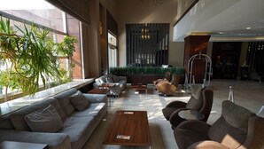 Un vestíbulo moderno con un sofá, sillones, una mesa de centro y un mostrador de recepción.
