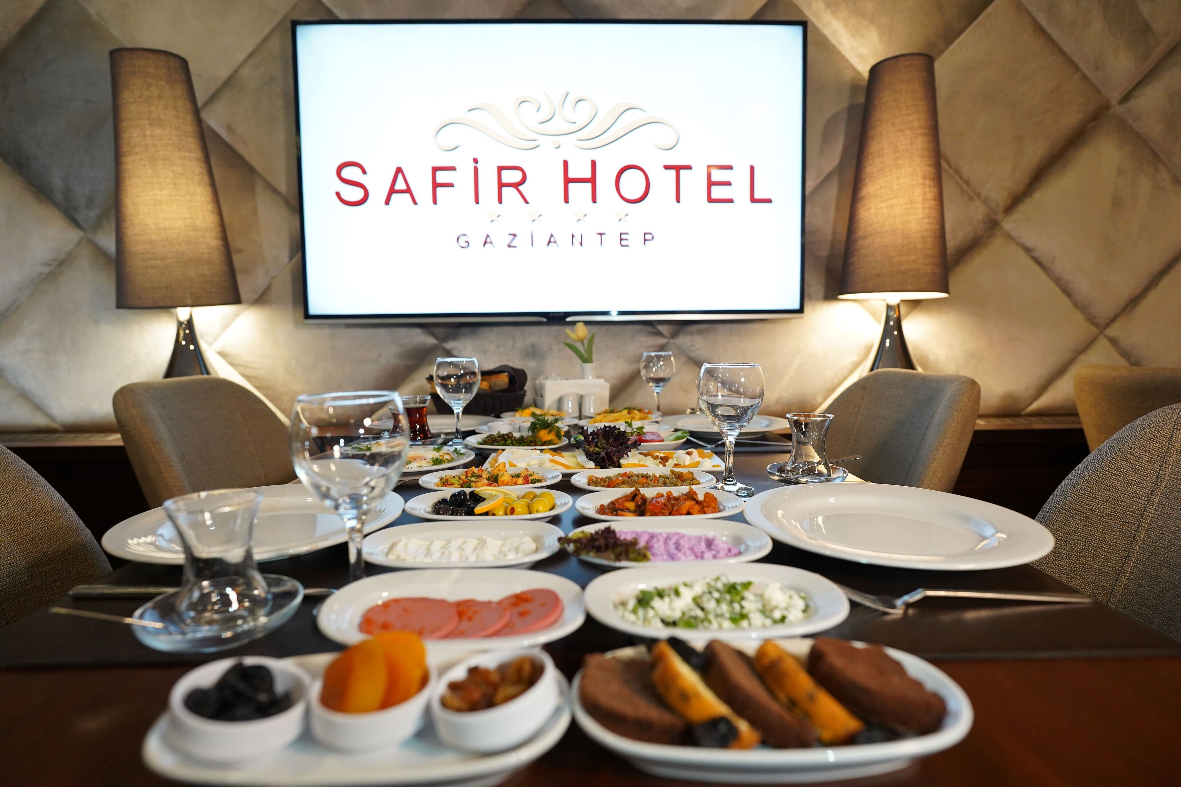 A dining table set for a meal at Safir Hotel in Gaziantep, with various dishes and glasses.