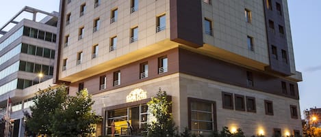 A multi-story hotel with a modern design, featuring a prominent sign on the facade and a well-lit entrance.