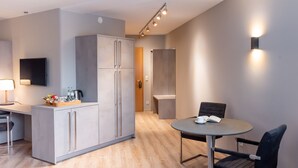 Una cocina moderna con refrigerador empotrado, un comedor con mesa redonda y sillas, y un televisor de pantalla plana montado en la pared.