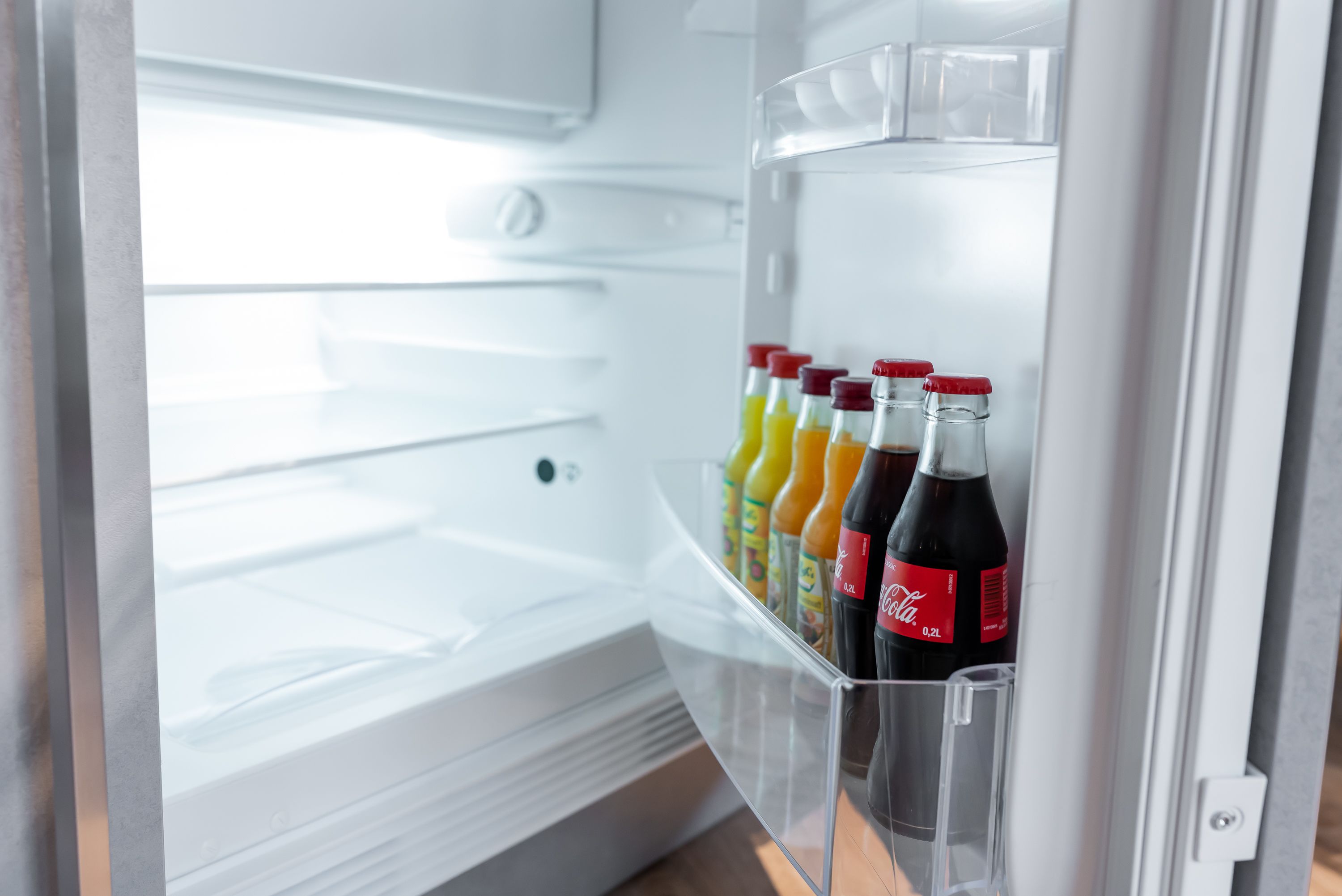 Un refrigerador abierto con dispensador de bebidas que contiene varias opciones.