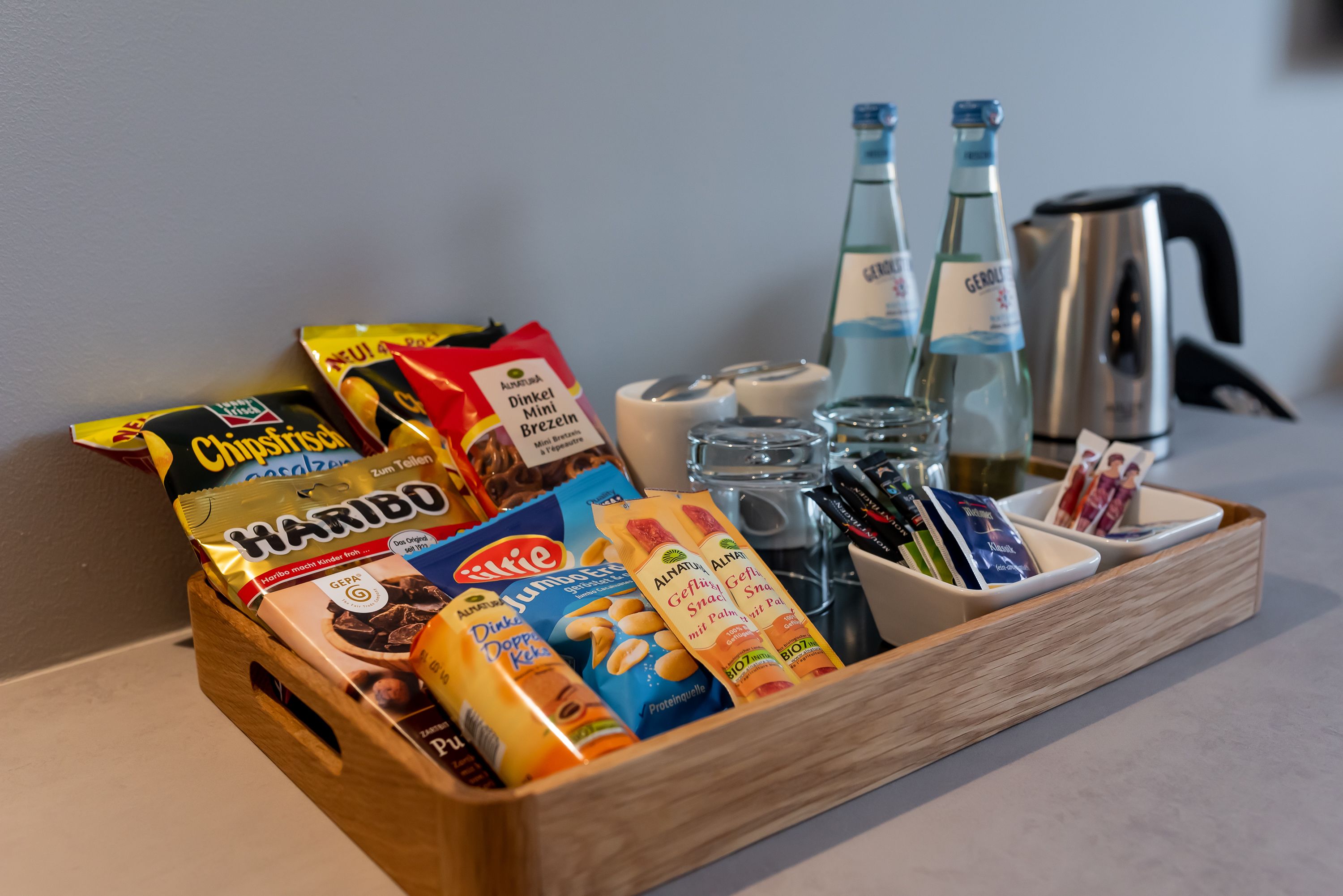 A wooden tray with snacks, beverages, and condiments.