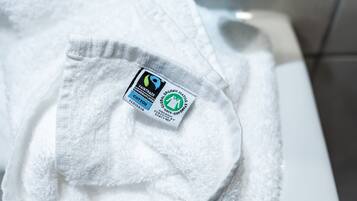 Una toalla blanca con etiqueta que indica que es de comercio justo, orgánica y certificada por la Norma Global Textil Orgánica.
