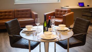 A dining area with a round table set for four, surrounded by leather sofas.