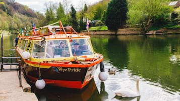 A boat docked at a pier with a swan swimming nearby.
