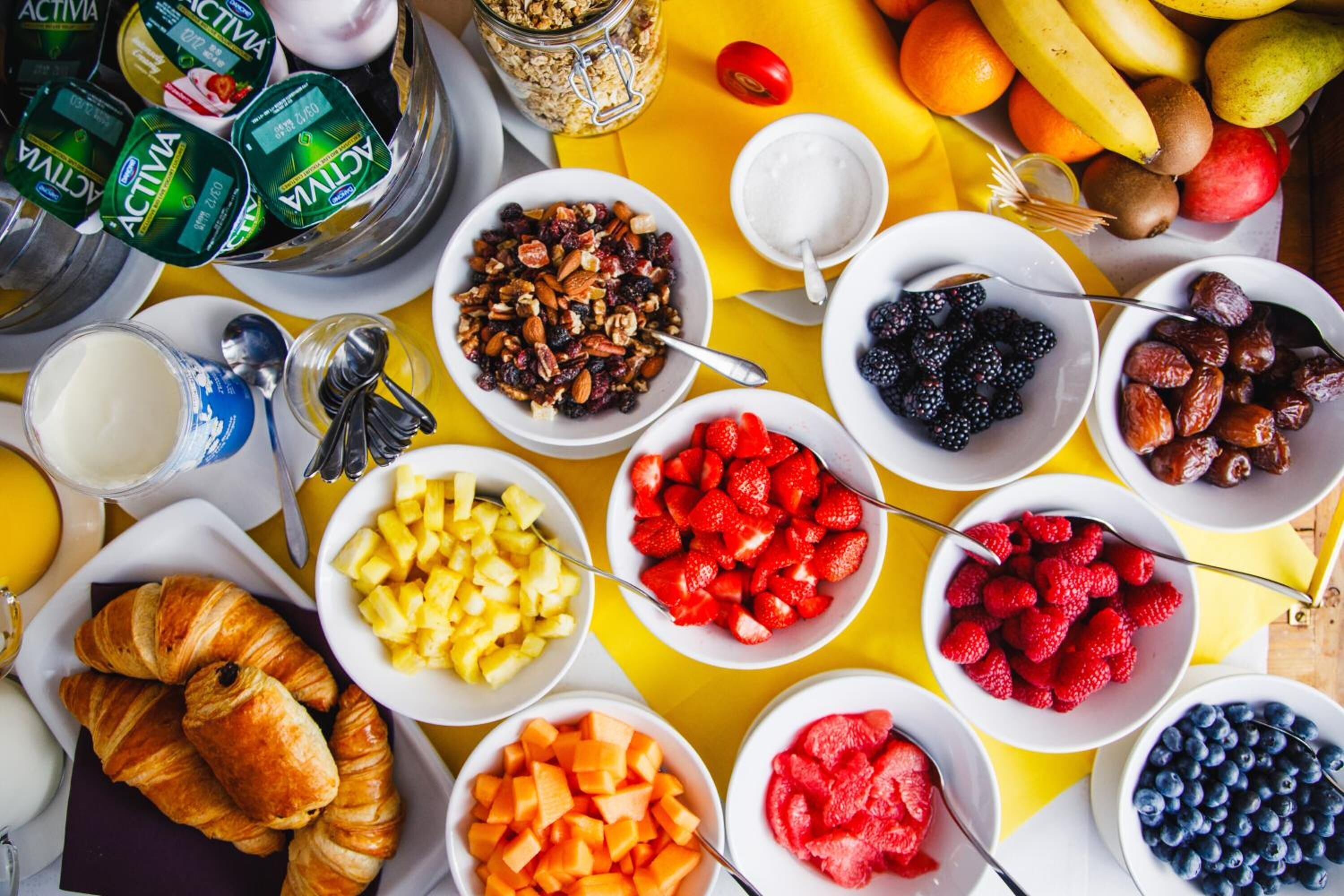 A breakfast spread with various fruits, nuts, and dairy products.