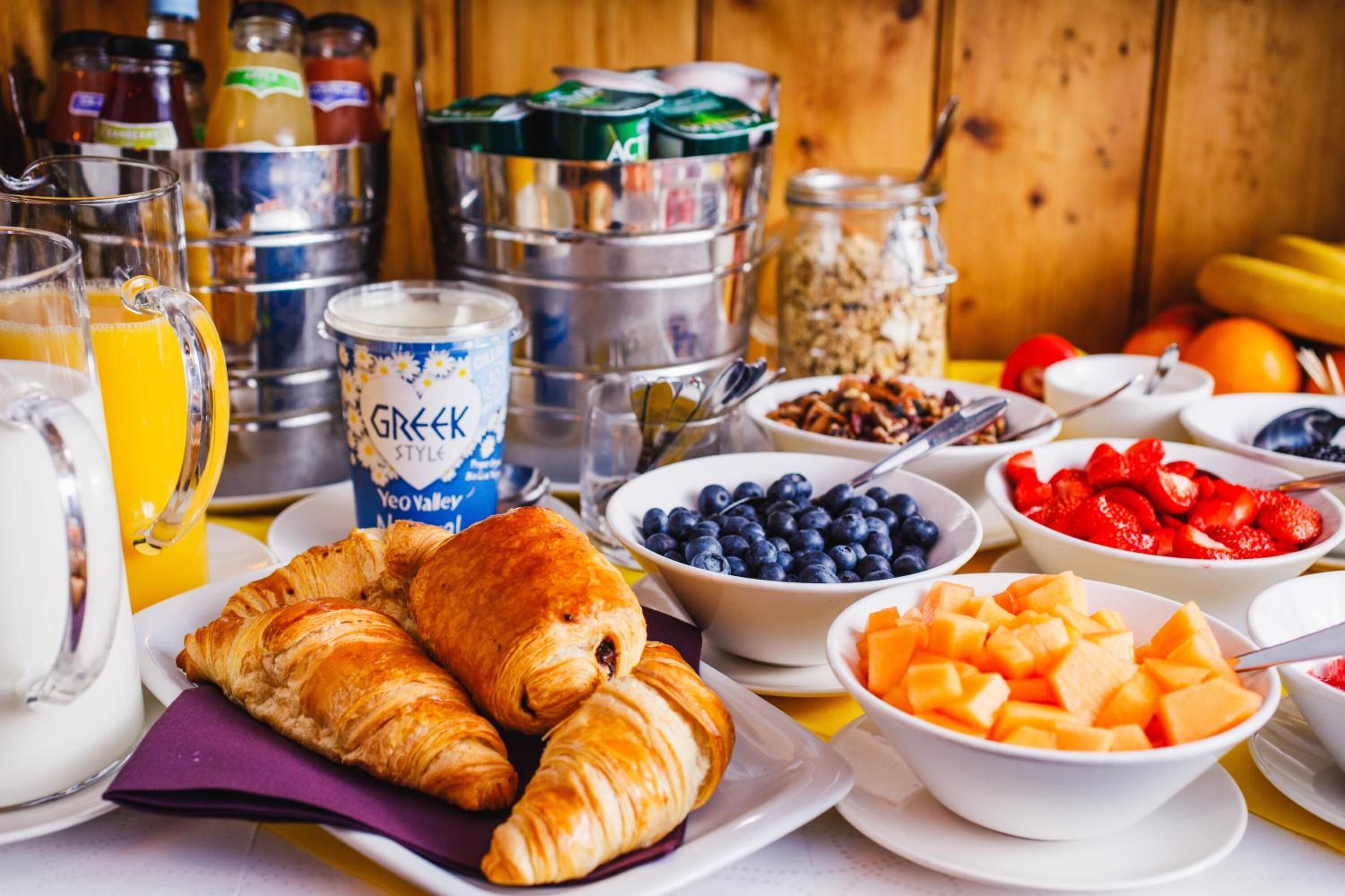 Un bufé de desayuno con cruasanes, frutas y bebidas.