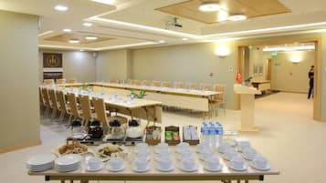 A conference room with a long table set for a meeting, equipped with water bottles, cups, and a projector.
