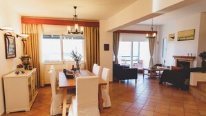 A spacious living room with a dining area, large windows, and a fireplace. - Wild Pear Villa (Malevizi)
