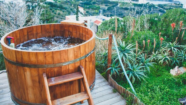 A wooden hot tub on a wooden deck with a view of a coastal town. - Wild Pear Villa (Malevizi)