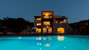 A modern two-story building with a swimming pool in front. - Wild Pear Villa (Malevizi)