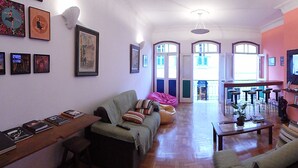 Uma sala de estar espaçosa com um sofá, uma mesa de centro e uma área de jantar com cadeiras.