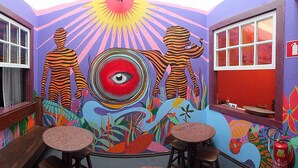 Quarto com um mural, duas mesas e um extintor de incêndio.