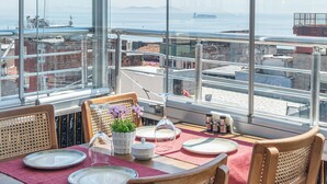 A dining area with a table set for four, large windows with a city view, and a balcony railing. - Oban Suites İstanbul (Istanbul)