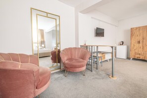 A modern room with a pink chair, a mirror, a wooden wardrobe, and a small dining table. - Oban Suites İstanbul (Istanbul)
